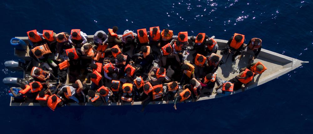 Migranten aus Eritrea, Libyen und dem Sudan sitzen in einem Holzboot, bevor sie von Helfern der spanischen Nichtregierungsorganisation Open Arms im Mittelmeer, etwa 30 Meilen nördlich von Libyen, unterstützt werden.
