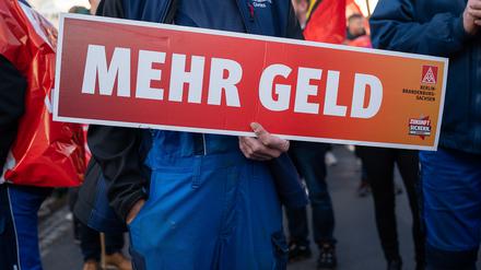 15.11.2022, Sachsen, Görlitz: Ein Mitarbeiter hält ein Schild mit der Aufschrift «Mehr Geld» in den Händen. Beschäftigte von Alstom und Siemens protestieren mit einem Warnstreik vor dem Werk von Siemens Energy. Foto: Paul Glaser/dpa-Zentralbild/dpa +++ dpa-Bildfunk +++