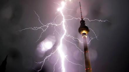 Ein Blitz schlägt neben dem Fernsehturm in Berlin ein. 