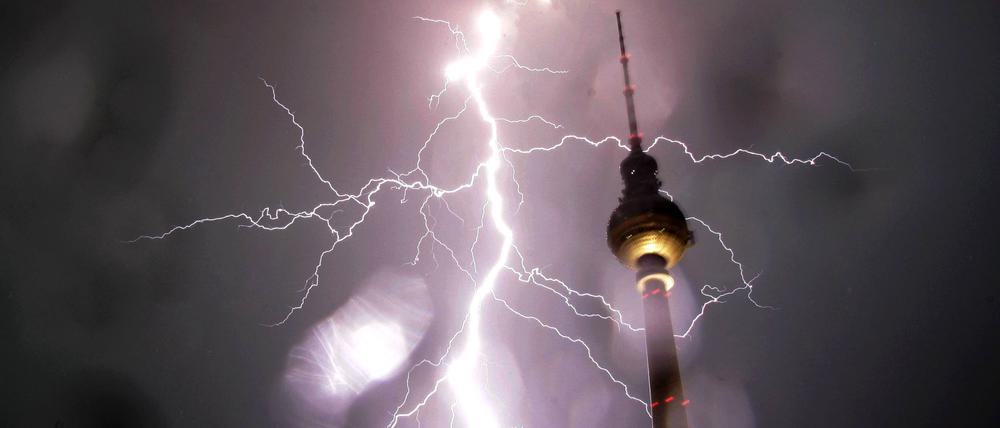 Ein Blitz schlägt neben dem Fernsehturm in Berlin ein. 