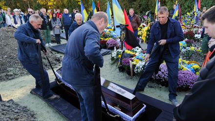 Lviv, Ukraine: Bestatter senken den Sarg des ukrainischen Soldaten Taras Havrylyshyn, eines ehemaligen Mitglieds der nationalen Pfadfinderorganisation Plast, ins Grab. 