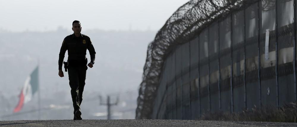 Der US-Grenzpolizist Eduardo Olmos läuft am 22.06.2016 entlang des Zauns an der Grenze zwischen USA und Mexiko in San Diego (USA).
