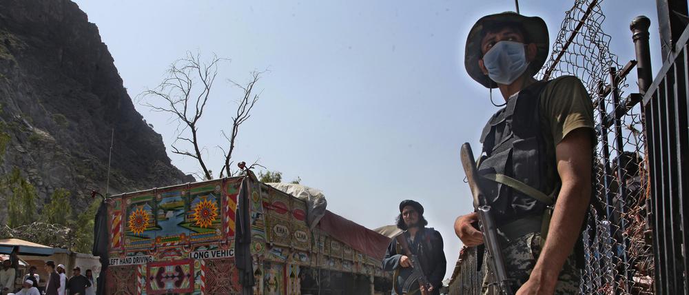 ARCHIV - 21.08.2021, Pakistan, Torkham: Ein pakistanischer Soldat (r) und Kämpfer der Taliban stehen Wache an einem Grenzübergang zwischen Pakistan und Afghanistan in der Provinz Khyber Pakhtunkhwa auf den jeweiligen Seiten der Länder. (zu dpa: «Sieben Tote bei Kämpfen an pakistanisch-afghanischer Grenze») Foto: -/AP/dpa +++ dpa-Bildfunk +++