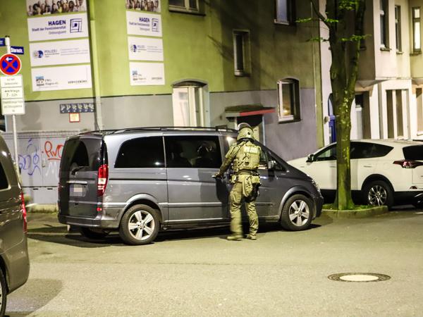 Ein Polizist steht während einer Razzia in Hagen (NRW) an einem Van.