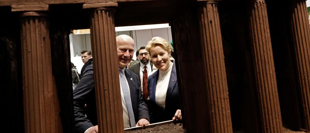 Kai Wegner (CDU), Regierender Bürgermeister von Berlin, und Franziska Giffey (SPD, r), Berliner Wirtschaftssenatorin, schauen beim Eröffnungsrundgang über das Messegelände der Grünen Woche in der Berlin Halle durch ein großes Brandenburger Tor aus Schokolade. 