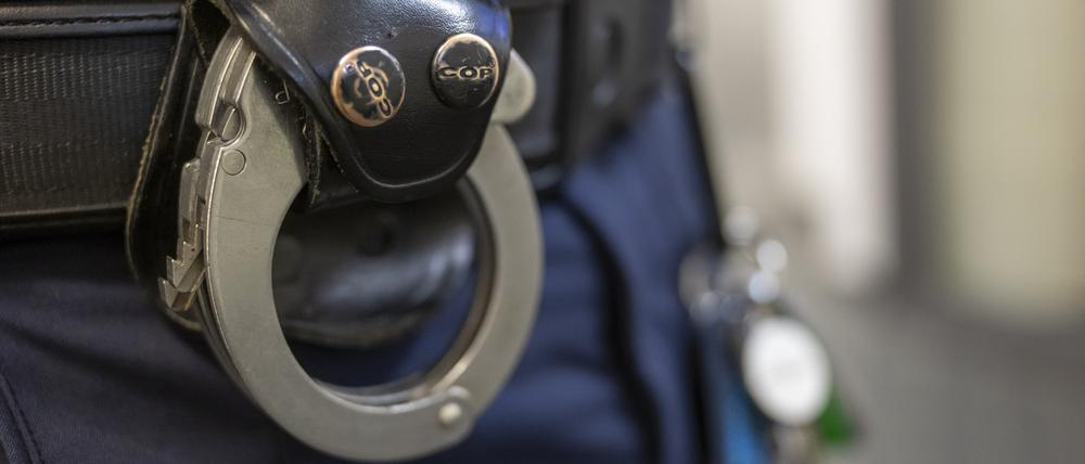 Eine Handschelle hängt am Gürtel eines Polizisten. (Symbolbild)