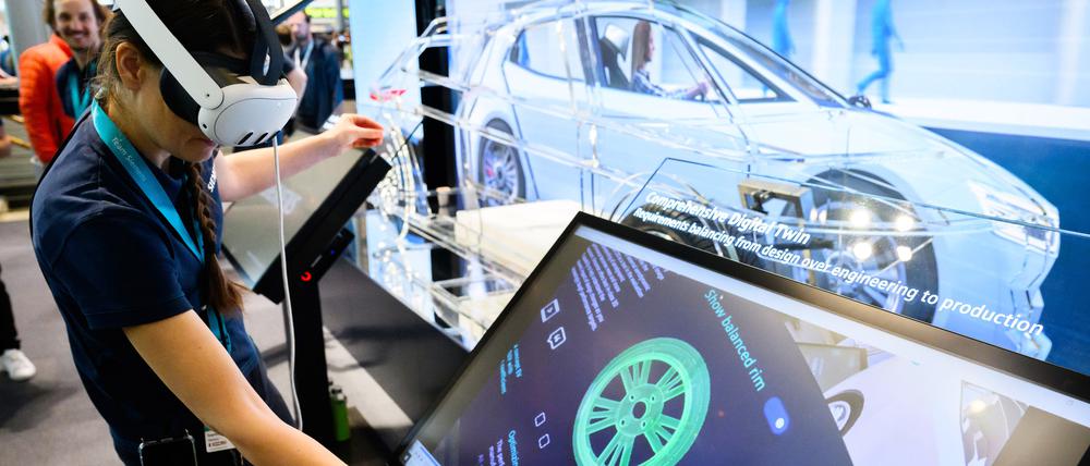 Eine Siemens-Mitarbeiterin steht mit einer AR-Brille (Augmented-Reality) auf der Hannover Messe und zeigt eine Simulation aus der Automobilindustrie.