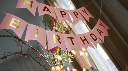  „Happy Birthday· steht auf einer Girlande, die über einem Geburtstagstisch hängt. 