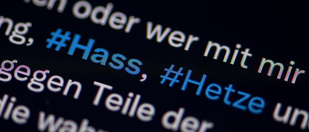 Auf dem Bildschirm eines Smartphones sieht man die Hashtags Hass und Hetze in einem Twitter-Post. 