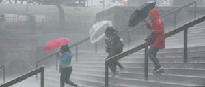 Vor dem Kölner Hauptbahnhof kämpfen Menschen mit starken Regenfällen.