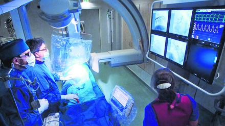 Alles im Blick im OP-Saal: Kardiologe Stephan Dreysse und sein Team verfolgen den Verlauf des Katheters während des Eingriffs in Echtzeit am Bildschirm.