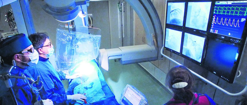 Alles im Blick im OP-Saal: Kardiologe Stephan Dreysse und sein Team verfolgen den Verlauf des Katheters während des Eingriffs in Echtzeit am Bildschirm.