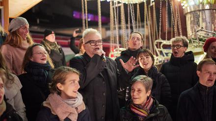 10.12.2023, Berlin: Bei einem Flashmob singt Herbert Grönemeyer mit dem Rundfunkchor sein neues Lied "Kaltes Berlin" auf dem Lucia Weihnachtsmarkt in der Kulturbrauerei. Foto: Joerg Carstensen/dpa +++ dpa-Bildfunk +++