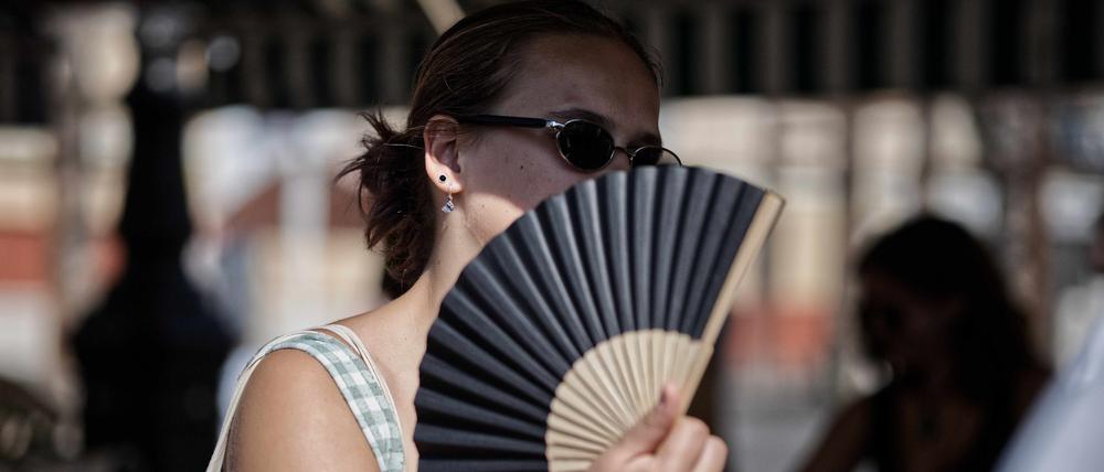 Eine Frau wedelt sich mit einem Fächer Luft zu. Die Hitzewelle in Frankreich nimmt an Intensität zu.