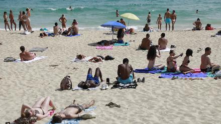 Menschen liegen in Spanien am Strand. 