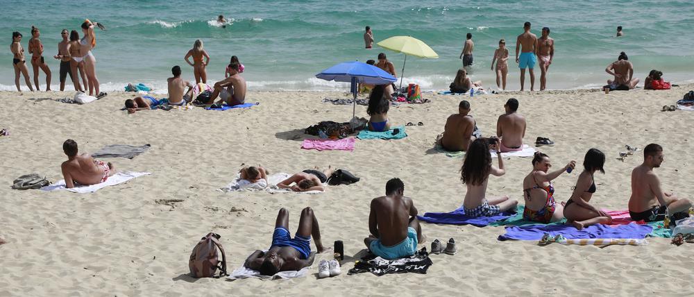Menschen liegen in Spanien am Strand. 