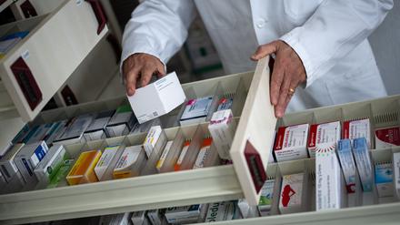 Ein Apotheker holt eine Medikamentenverpackung aus einer Schublade. 