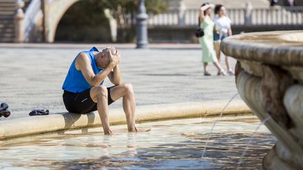 Ein Mann kühlt sich im Juli 2022 im zentralen Brunnen auf der Plaza de España in Sevilla ab.
