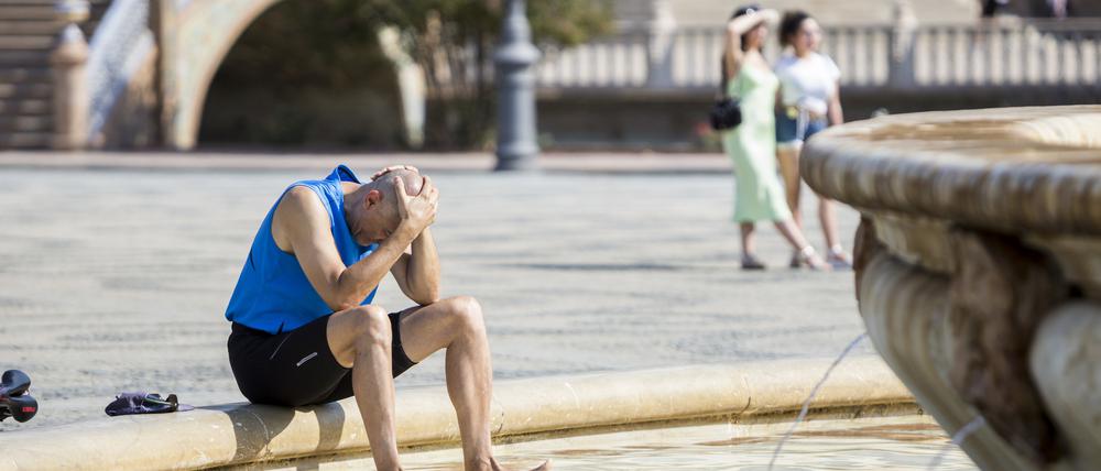 Ein Mann kühlt sich im Juli 2022 im zentralen Brunnen auf der Plaza de España in Sevilla ab.
