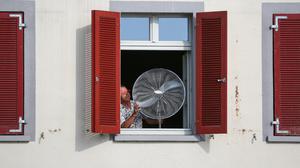 Mit einem Ventilator im offenen Fenster versucht ein Bewohner von Riedlingen, Baden-Württemberg, die Hitze des vergangenen Sommers zu lindern.