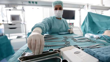 Eine OP-Schwester greift in einem Hamburger Krankenhaus nach einer Zange.