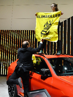 Kanzlerin Angela Merkel (CDU) bei der Internationales Automobilausstellung in Frankfurt - und eine Aktivistin von Greenpeace auf einem Auto.