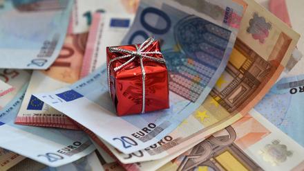 Ein rotes Geschenkpaket mit einer silbernen Schleife liegt auf Geldscheinen. (Symbolfoto)