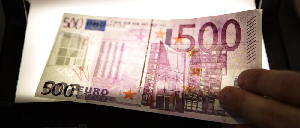Ein gefälschter 500-Euro-Schein wird von einem Prüfgerät durchleuchtet (Symbolfoto).