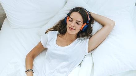 Young woman sleeping in bed at home with headphones model released Symbolfoto property released PUBLICATIONxINxGERxSUIxAUTxHUNxONLY KIJF02565