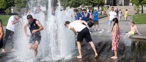 Personen kühlen sich an einem heißen Sommertag am Springbrunnen im Lustgarten auf der Museumsinsel im Bezirk Mitte ab. 