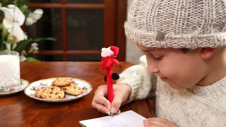 Ein Kind schreibt einen Weihnachtswunsch auf einen Zettel.