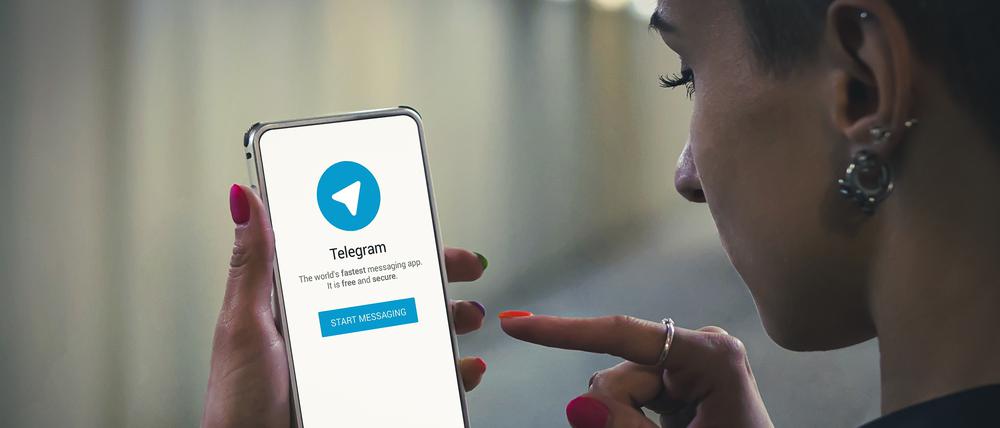 Eine junge Frau startet Telegram auf dem Smartphone.