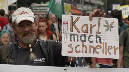 Ein Mann hält auf der Hanfparade 2023 am Berliner Alexanderplatz ein Schild mit der Aufschrift „Karl mach schneller“