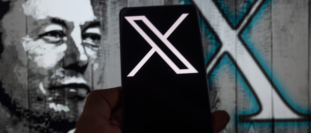 Elon Musk neben einem Handy mit dem X-Logo.