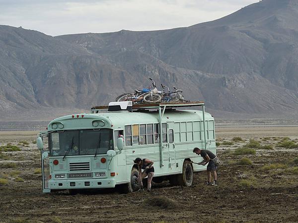 Festgefahrene Situation: Festival-Teilnehmer versuchen, ihren Bus aus dem Wüstenschlamm zu befreien.