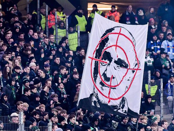 Hannover-Fans mit halten Banner hoch, das ein Fadenkreuz über dem Gesicht von Hannover 96-Geschäftsführer Martin Kind zeigt.