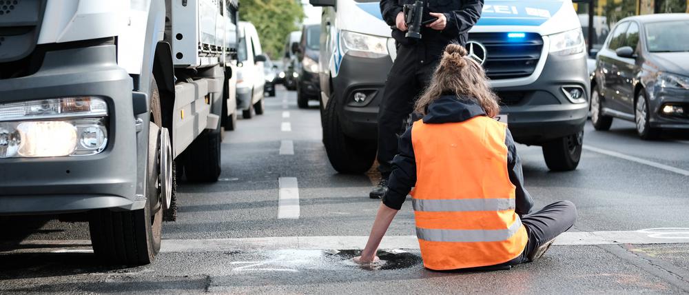  Klimaaktivisten blockieren eine Straße.