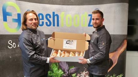 Freshfoodz-Chef Karsten Streeck (l.) und sein Mitarbeiter Lucas Gerigk mit einer „Genussbox“, die sieben Gerichte enthält.