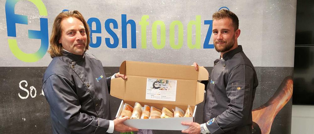 Freshfoodz-Chef Karsten Streeck (l.) und sein Mitarbeiter Lucas Gerigk mit einer „Genussbox“, die sieben Gerichte enthält.