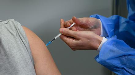 Eine Person lässt sich in einem Impfzentrum gegen Corona immunisieren. 