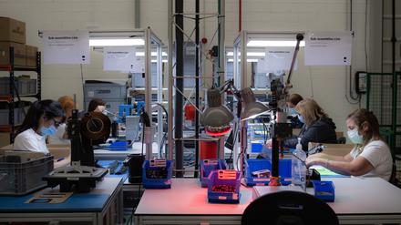 Frauen arbeiten in einer Fabrik, die Ladegeräte für Elektroautos herstellt. 