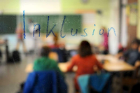 Auf einer aufgeklappten Tafel in einem Klassenraum steht "Inklusion".