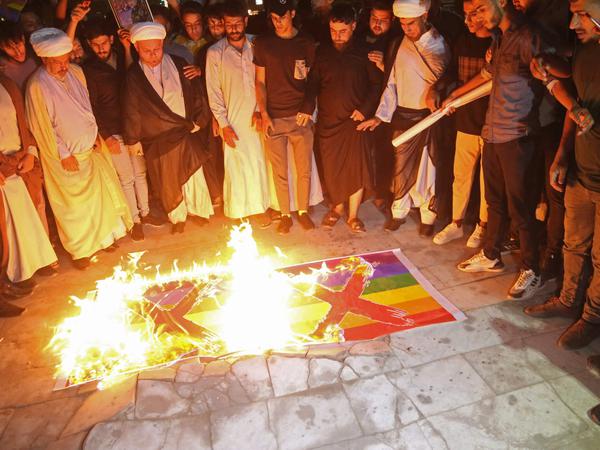 Demonstranten im Irak Plakate mit einer LGBTQ+-Flagge und verurteilen die Koranverbrennung in Schweden. 