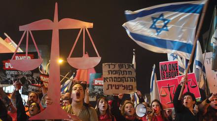 Israeli protesters lift placards and they chant slogans during a rally in central Tel Aviv, on February 11, 2023, against controversial legal reforms being touted by the country's hard-right government. (Photo by JACK GUEZ / AFP)
