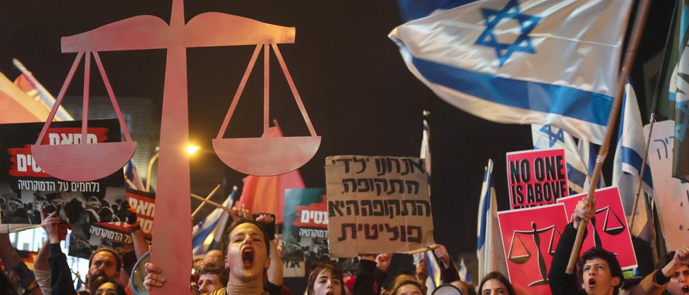 Israeli protesters lift placards and they chant slogans during a rally in central Tel Aviv, on February 11, 2023, against controversial legal reforms being touted by the country's hard-right government. (Photo by JACK GUEZ / AFP)