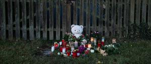 Kerzen, Blumen und ein großer Plüschteddy sind vor einem Zaun am Fundort zu sehen, wo die Leiche einer vermissten 14-Jährigen aus Nordhessen in einem Waldstück gefunden wurde.