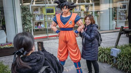 Ein „Dragon-Ball“-Fan in Tokio neben einer Statue der Hauptfigur Son Goku.
