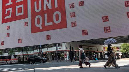 Pedestrians are reflected in a mirror outside a branch of the Fast Retailing clothing brand Uniqlo along a street in downtown Tokyo on July 10, 2023. (Photo by Richard A. Brooks / AFP)