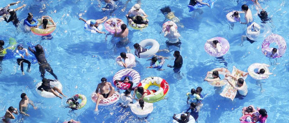 Ein Foto aus einem Hubschrauber zeigt Menschen mit Schwimmreifen in einem Schwimmbad. 