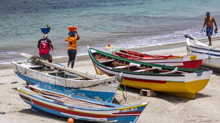 Zwei einheimische kapverdische Frauen transportieren Lebensmittel auf dem Kopf am Strand bei Tarrafa auf der Insel Santiago auf den Kapverden. 